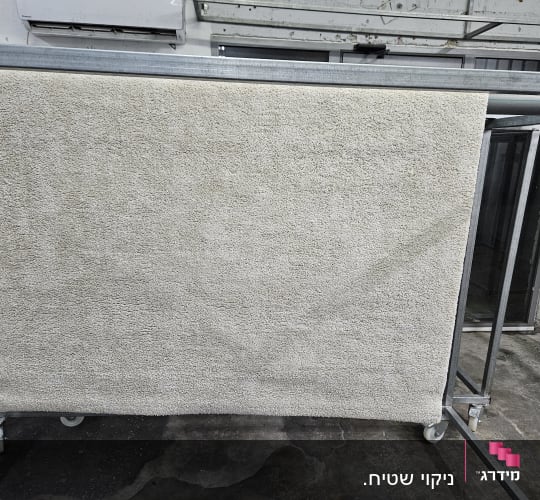 שטיח תלוי לייבוש על מתקן מתכת